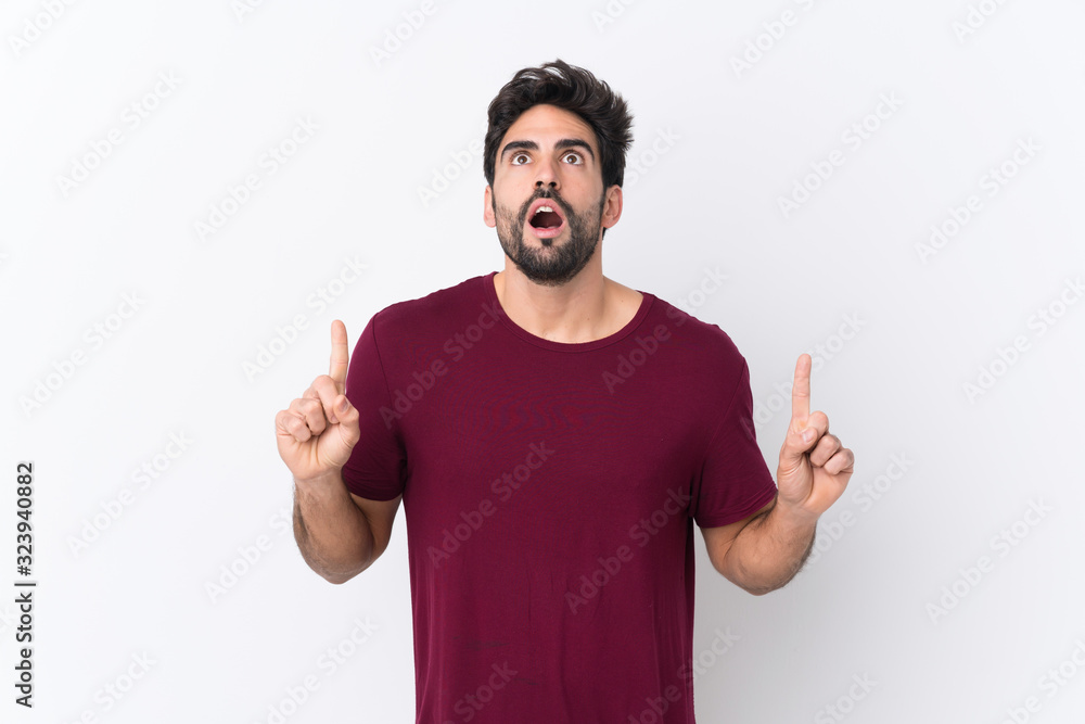 Young handsome man with beard over isolated white background surprised and pointing up Young handsome man with beard over isolated white background surprised and pointing up