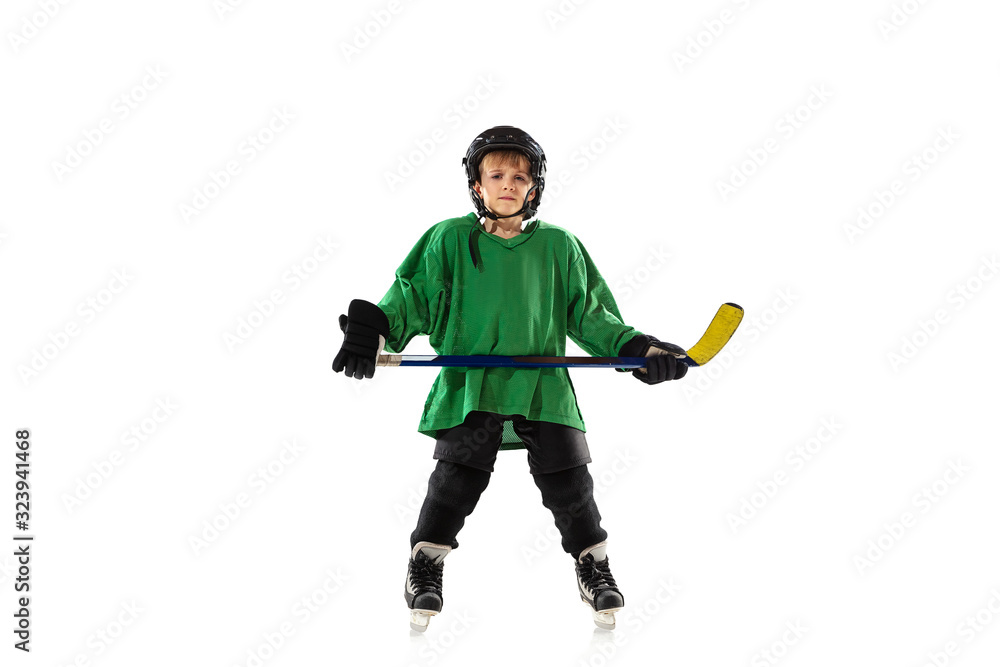 Little hockey player with the stick on ice court, white studio background. Sportsboy wearing equipment and helmet, practicing, training. Concept of sport, healthy lifestyle, motion, movement, action.