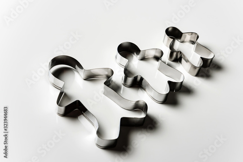 Three cookie cutters in the form of men of different sizes on a white background. photo