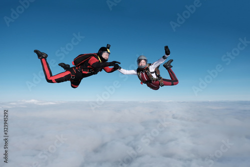 Skydiving. Guy and girl fly together in the sky above white clouds