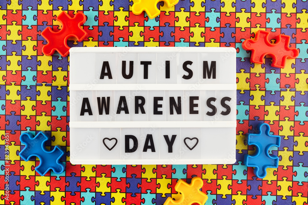 Light box with World autism awareness day text on colored puzzle background. Top view Light box with World autism awareness day text on colored puzzle background. Top view