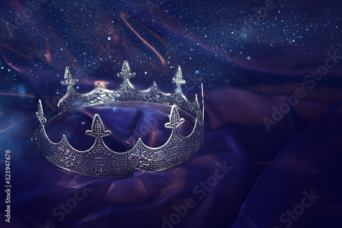 low key image of beautiful queen/king crown over dark royal purple delicate silk. fantasy medieval period