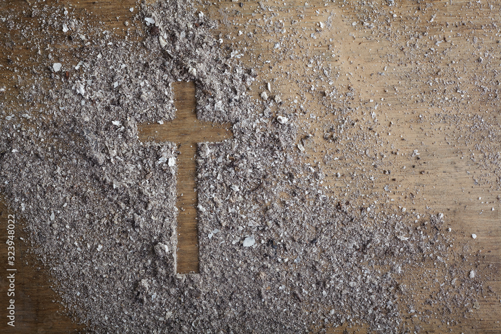Christian cross symbol made of ash on a wooden background