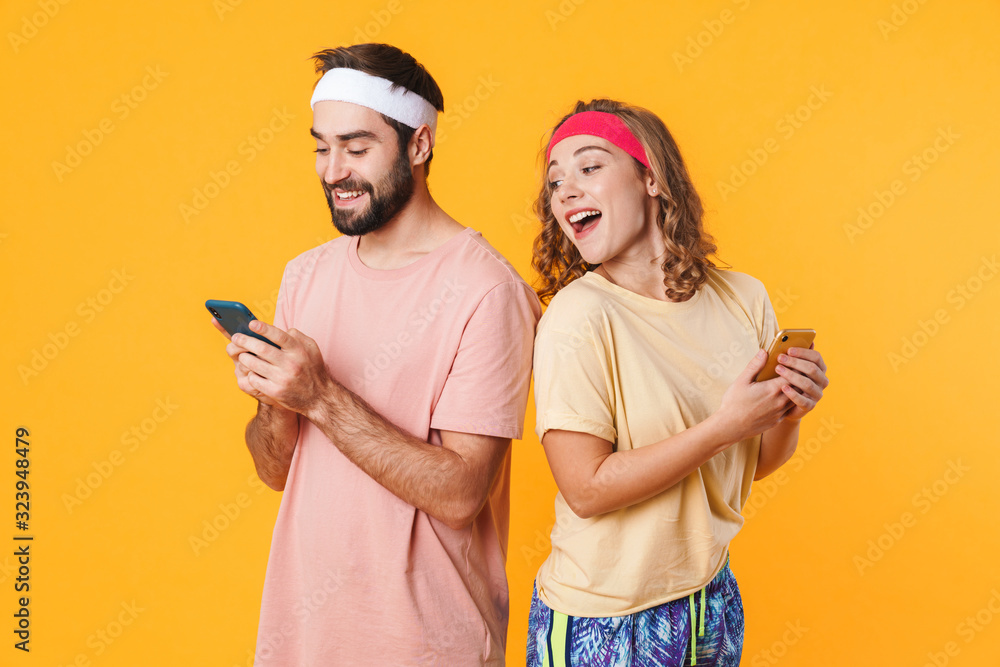 Portrait of athletic young couple smiling and using cellphones together Portrait of athletic young couple smiling and using cellphones together