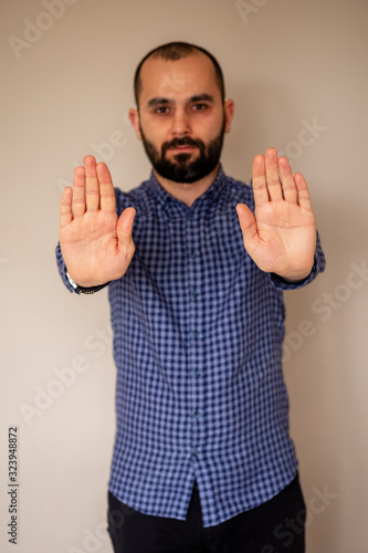 Close-up of Young Man's Hand. Young Muslim man with beard making stop gesture with both hands. Stop against racism and Islamophobia.