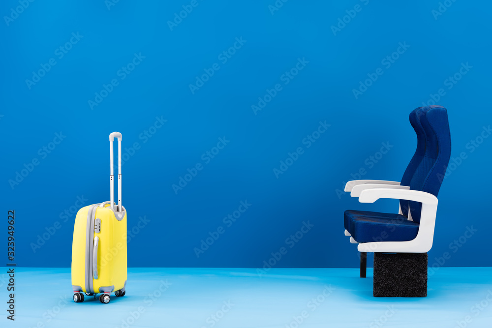 Obraz premium yellow travel bag and seats on blue background
