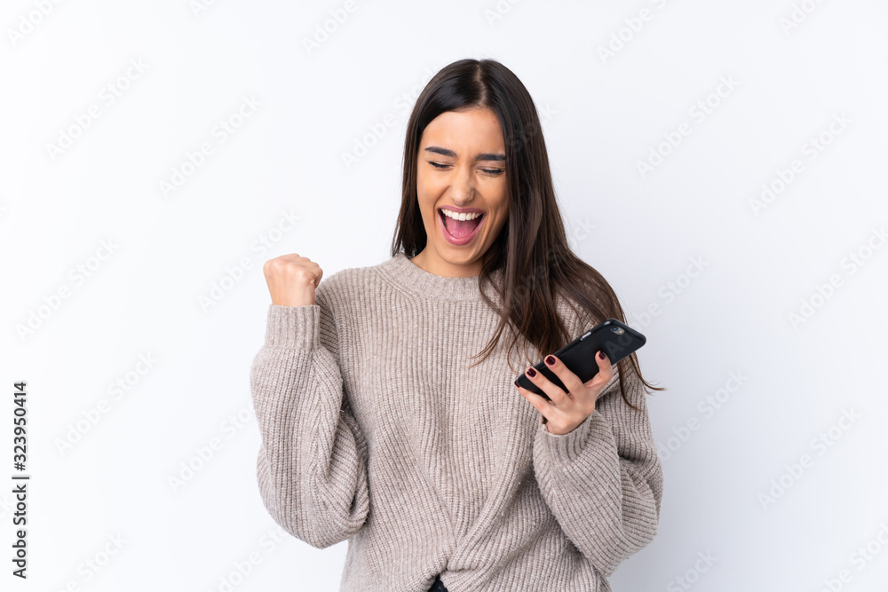 Young brunette woman over isolated white background with phone in victory position Young brunette woman over isolated white background with phone in victory position