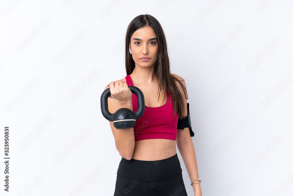 Young sport brunette woman over isolated white background making weightlifting with kettlebell and looking to the front Young sport brunette woman over isolated white background making weightlifting with kettlebell and looking to the front