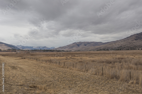 Vast open fields with cattle fencing in front of large rolling hill mountains