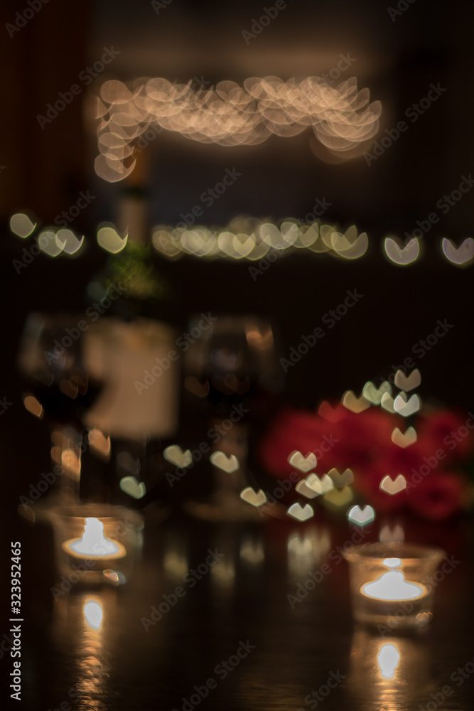 Abstract defocused background of red wine and roses on dark table for romantic dinner date night heart bokeh