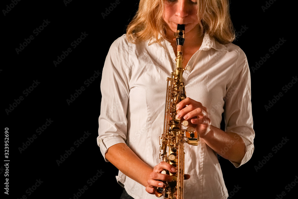 Fototapeta premium soprano saxophone in the hands of a girl on a black background