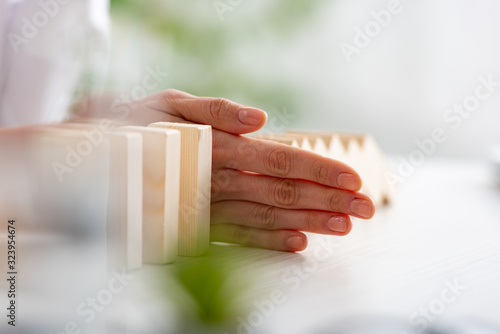 Selective focus of businesswoman folding falling building blocks on table on grey background