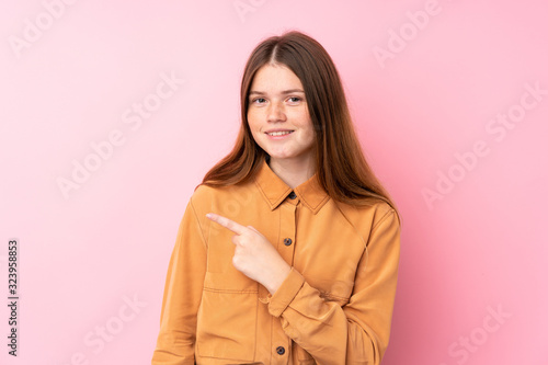 Ukrainian teenager girl over isolated pink background pointing to the side to present a product