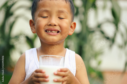 An Asian boy is drinking milk from a large glass.