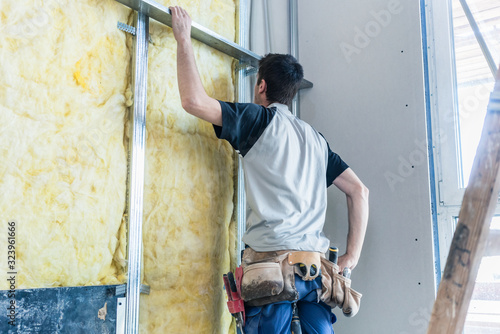 Worker insulating wall of a new building on construction site photo