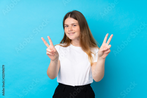 Ukrainian teenager girl over isolated blue background smiling and showing victory sign