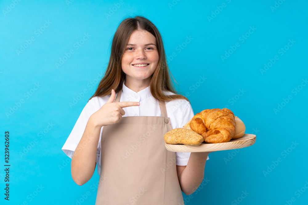 Ukrainian teenager chef uniform. Female baker holding a table with several breads and pointing it Ukrainian teenager chef uniform. Female baker holding a table with several breads and pointing it