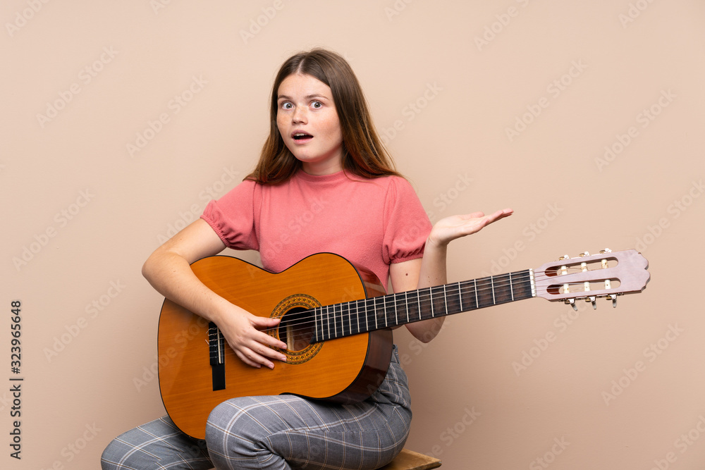 Ukrainian teenager girl with guitar over isolated background with shocked facial expression Ukrainian teenager girl with guitar over isolated background with shocked facial expression
