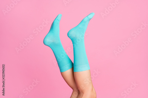 Cropped close-up view of nice feminine legs wearing blue soft cotton bright cosy comfy socks hosiery isolated over pink pastel color background