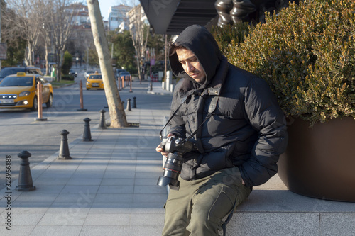 Young photographer looking at his photos on the street