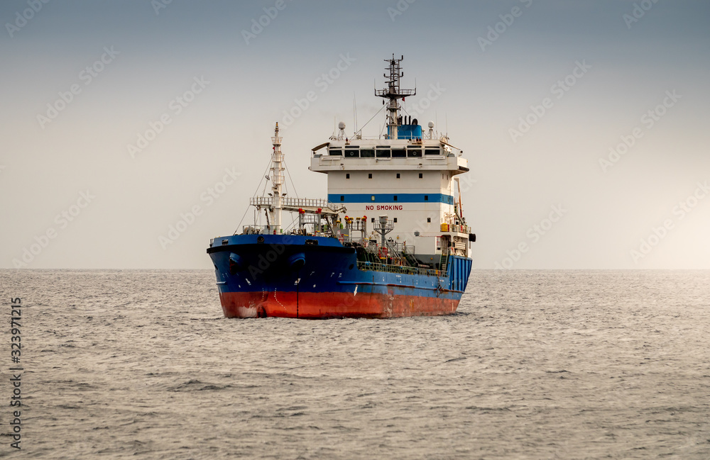 Beautiful image of old rusty cargo ship or oil tanker in the ocean at sunset light