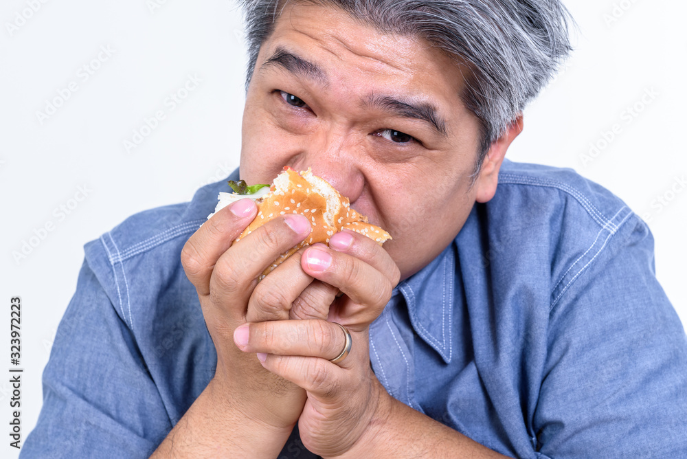 Close up images of Asian middle aged men Eating bread from a hamburger With hunger On white background, to people and food concept. Close up images of Asian middle aged men Eating bread from a hamburger With hunger On white background, to people and food concept.