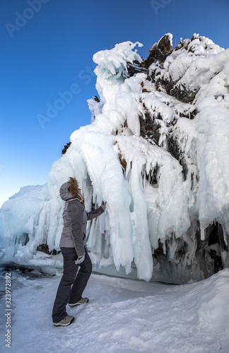 Woman marvelling at the massive wall of ice formed as a result of waves and wind. Lake Baikal, Siberia, Russia.
