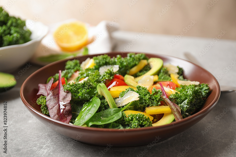 Tasty fresh kale salad on light grey table, closeup