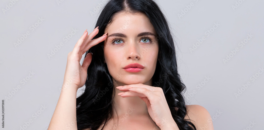 Fototapeta premium Beautiful young woman touching her face in skin care theme