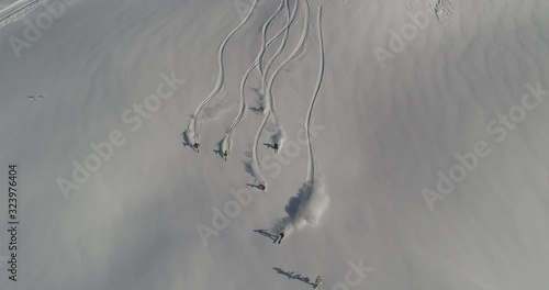 Aerial slow motion: five skiers and one snowboarder ride the first freeride line. off-piste skiing, Heli skiing. freeriders roll out large untouched snow valleys. Freeride ski & Epic free ride scene
