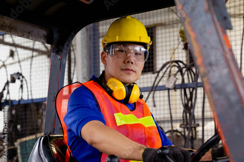 A man with yellow safety helmet and goggles driving a forklift or reach  truck  at the logistics warehouse store. Industrial, Mechanic, Engineering Concept. 