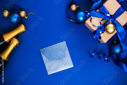 Little confert with a white piece of paper on a blue background with champagne, toys, gifts.