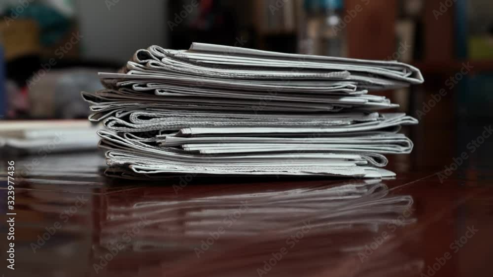 A pile of newspaper moving into the middle of frame by hand