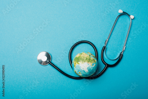 Top view of globe and stethoscope on blue background, world health day concept photo