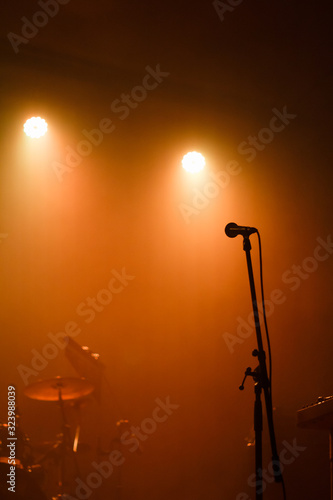 Microphone on the stage and musical instruments filled with orange light
