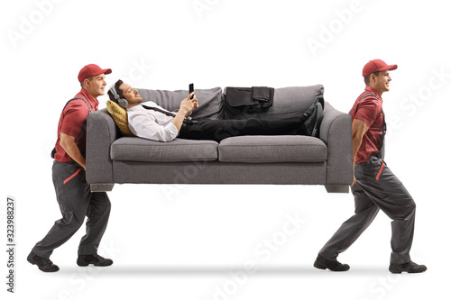 Two movers carrying a man with headphones on a sofa photo