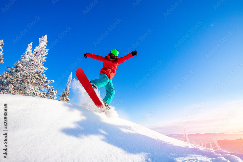 Snowboarder jumping through air with deep blue sky from hill