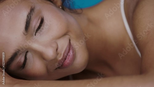 close-up of fresh woman face with dark eyes and eyebrows natural make-up lying on her arm smiling to camera