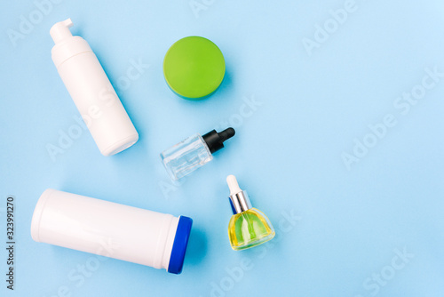 White plastic bottles on a blue background. Cosmetic products for women, foam for washing, foundation for makeup and oil. Health and beauty.