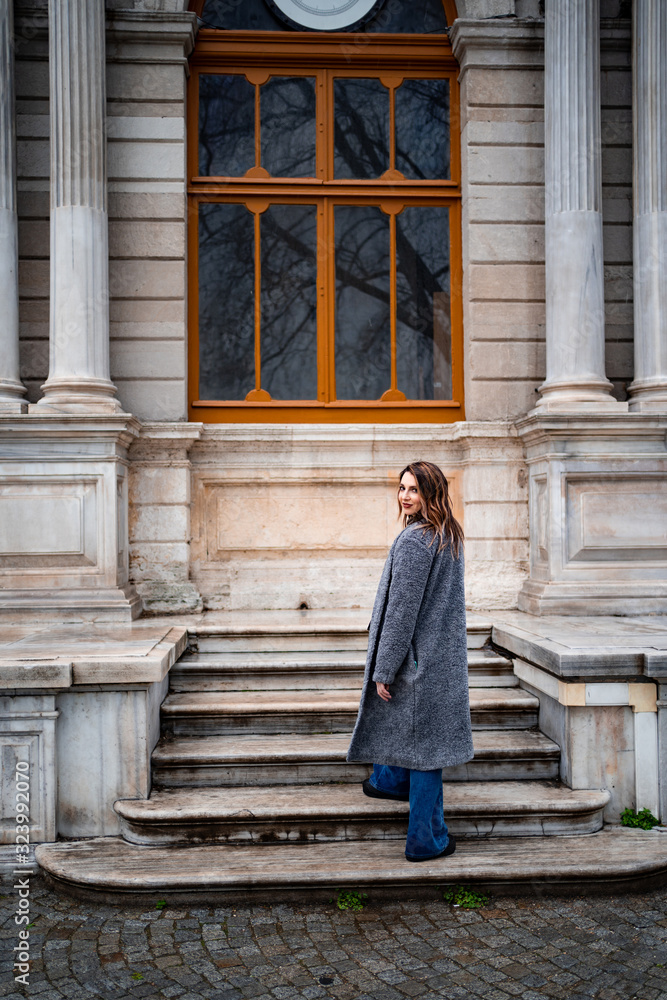 a girl stands on the steps of an old building in the rain