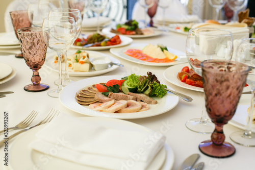 Served for banquet restaurant table with dishes  snack  cutlery  wine and water glasses  european food  selective focus