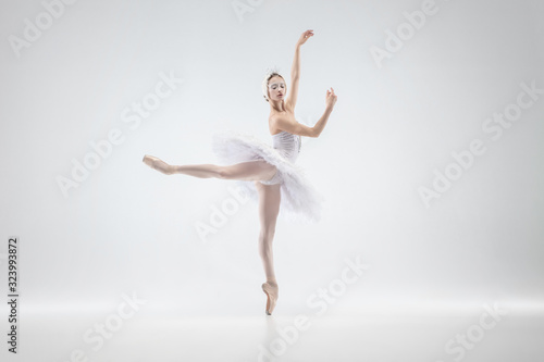 Fototapeta Naklejka Na Ścianę i Meble -  Graceful classic ballerina dancing isolated on white studio background. Woman in tender clothes like a white swan characters. The grace, artist, movement, action and motion concept. Looks weightless.