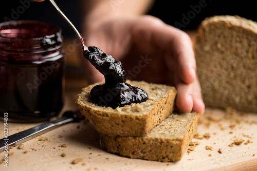 Obraz na plátně Person applying blueberry jam on fresh slices of bread, close-up of the moment w