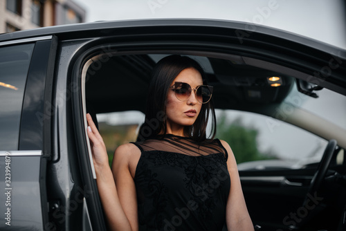 Stylish young girl sitting in a business class car in a black dress. Business fashion and style © Andrii