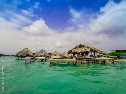 Ocean bar in Cholon beach. Tropical hut seats inside turquoise blue sea at the beach by Baru - Cartagena in Colombia