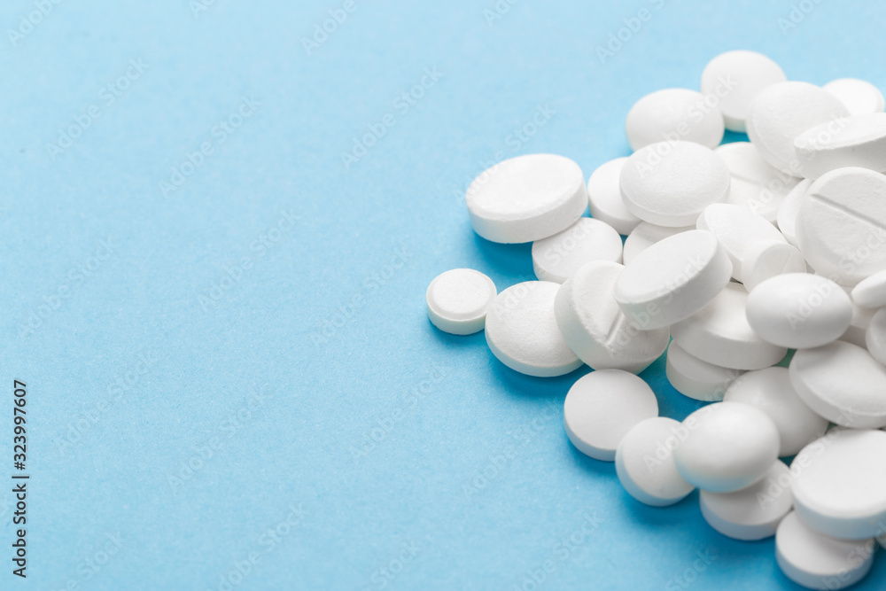 scattered white pills on a blue table. Layout for special offers such as advertising or other ideas. The concept of medicine, pharmacy and healthcare. Space for copy. flat lay for text or logo. scattered white pills on a blue table. Layout for special offers such as advertising or other ideas. The concept of medicine, pharmacy and healthcare. Space for copy. flat lay for text or logo.