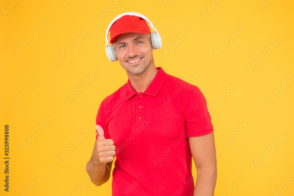 Audio guide. Man listen music headphones. Incoming call. Worker in uniform with earphones. Man in headphones on yellow background. Assistant call center help find solution. Guy call service worker
