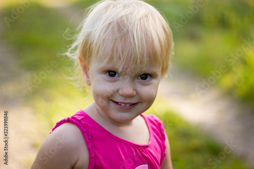Portrait of a cute blond toddler girl wearing pink dress on a beautiful sunny summer day