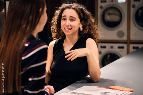 Slika na platnu Beautiful smiling brunette girl happily talking with friend waiting washing in m