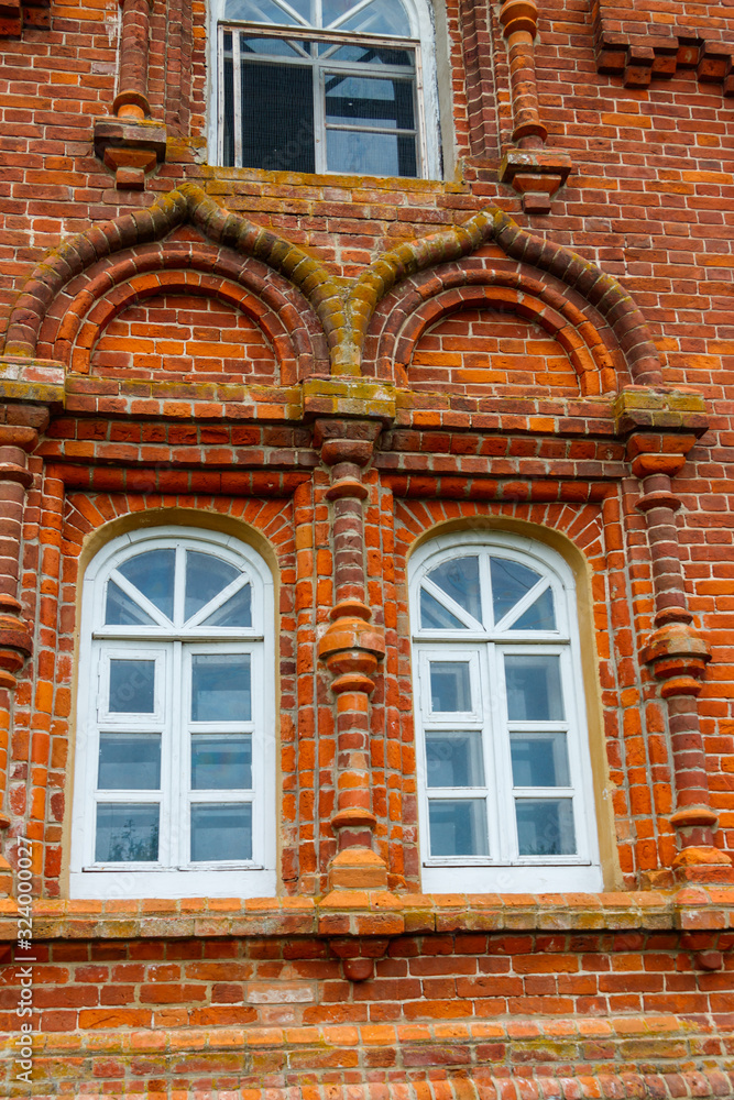 Two rounded windows on old red brick wall